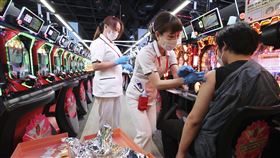 打疫苗出現過敏反應，日本官方決定給醫療補助，圖為醫護進駐小鋼珠店幫顧客接種疫苗。（圖／美聯社／達志影像）