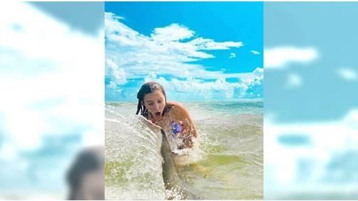 女子海邊嬉戲　合照時「鯊魚」搶曝光