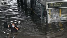 超強風暴「巴洛斯」侵襲希臘，首都雅典慘遭大水淹沒，圖為雅典南部一名公車司機疏散乘客後涉水離開畫面。（圖／美聯社／達志影像）