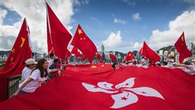 港府發表長文，重申國家安全屬於北京中央事權，北京在「一國兩制」的方針下有權立國安法。圖為2020年7月1日香港市民揮動中國國旗和區旗。（圖／中新社）
