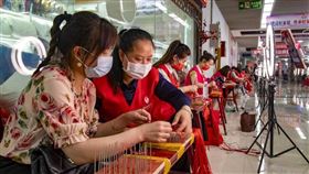 中國官方5日公布新增COVID-19病例539例，當前中國疫情延燒至浙江省，境內號稱全球零售業重鎮的義烏市也因爆發疫情而全面封城。圖為6月義烏小商品城市場裡，婦女編織中國結，並進行直播銷售。（中新社）