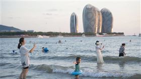 近日海南成最新疫情熱點，多城實施靜態管理，數萬名遊客滯留當地，傳有飯店漲價發疫情財引爆批評。圖為7月27日遊客在海南三亞灣戲水遊樂。（圖／中新社）
