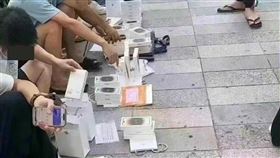 黃牛擺地攤求售蘋果手機。（圖／翻攝自《極目新聞》）
