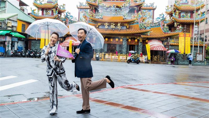 《花路阿朱媽》導演何書銘(右)與女主角洪慧芳(左)拿著本片特製導遊旗,共同造訪松山慈祐宮。(圖/采昌提供)