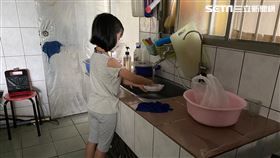 為了早日獨立自主，7歲的泡泡每天練習做家事。身高不夠的她學洗碗必須踩在椅凳上，才能符合流理台的高度。（圖／中信慈善基金會提供）