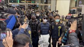 ▲88槍擊案「紅龜」洪政軍(中，白外套遮手)和槍手孔祥志被押抵回台南。警方仍重裝戒備不敢大意。（圖／翻攝畫面）