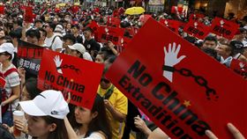 2019 年香港抗議者舉著標語牌在街上遊行。（圖／美聯社／達志影像）