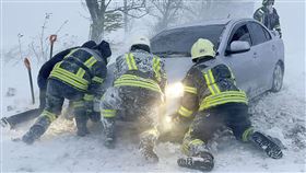 救援人員在烏克蘭高速公路上試圖推動一輛被雪困住的汽車。（圖／美聯社／達志影像）