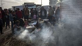 因以色列轟炸而流離失所的巴勒斯坦人，在加薩Muwasi區的臨時營地等待烤好的麵包。（圖／美聯社／達志影像）