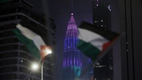 大馬社運人士揮旗幟表達聲援巴勒斯坦訴求大馬吉隆坡地標國油雙峰塔跨年夜以變色燈光秀取代煙火秀，圖為社運人士凌晨在變色燈光秀展開之際在美國使館前揮舞旗幟，表達聲援巴勒斯坦訴求。中央社記者黃自強吉隆坡攝  113年1月1日