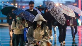 北台灣飄雨降溫（1）中央氣象署指出，16日晚間起大陸冷氣團南下，中部以北、宜蘭低溫約攝氏15、16度，其他地區約18、19度，提醒民眾留意溫度變化，適時保暖。圖為基隆港周邊傍晚飄著細雨，行人過馬路撐傘、戴帽遮擋。中央社記者吳家昇攝  112年11月16日
