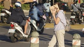 高雄地區高溫炎熱（3）中央氣象署1日下午更新高溫資訊，受西南風沉降影響，各地天氣高溫炎熱，高雄地區傍晚時刻陽光仍刺眼，前鎮區街頭民眾舉起手中物品遮擋斜射光線。中央社記者董俊志攝  113年7月1日