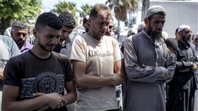 龍鳳胎的父親庫姆桑（中）在身亡的孩子旁祈禱。（圖／美聯社／達志影像）