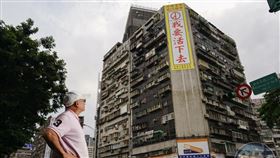 ▲錦新大樓去年發生多起跳樓自殺事件。大樓管委會主委周朝陽於大樓外牆掛上廣告看板，期盼尋死者看到後能轉念。