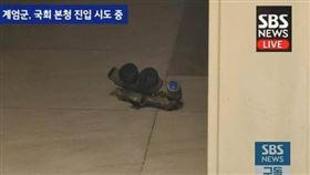 韓國新聞台畫面突然對焦地上的一副裝備，才發現是軍用四眼夜視鏡，要價4萬美金，合台幣129萬。（圖／翻攝自PTT）