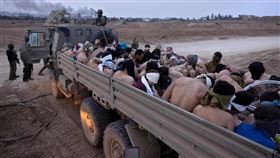 ▲2023年12月，以色列軍人站在一輛擠滿巴勒斯坦囚犯的卡車旁。（圖／美聯社／達志影像）