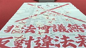 民進黨團今（4/11）天未再佔領主席台，在放大版議事錄上打叉叉，表達不滿。（圖／翻攝自沈伯洋臉書）