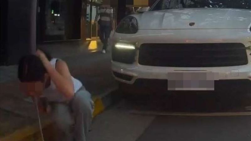 長髮女子從保時捷副駕下車後，熟練抓起頭髮蹲地並吐出一坨濃白液體，全程被前車「哨兵模式」錄下。（圖／翻攝自WoWtchout - 地圖型行車影像分享平台YouTube）