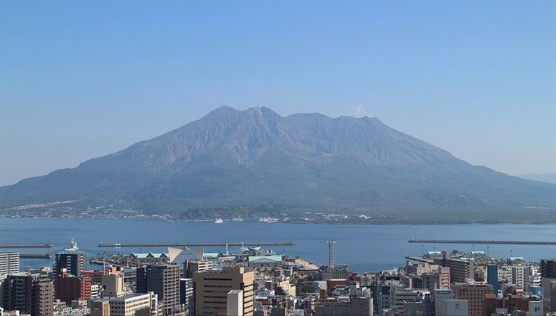 日本鹿兒島縣自6月下旬起地震不斷;圖為櫻島與鹿兒島市市區。(圖/翻攝自維基百科)