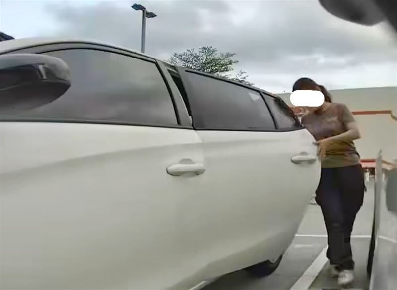女子將破碎酒瓶踢進特斯拉車底。(圖/翻攝爆料公社公開版)