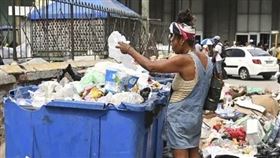 古巴首都哈瓦那，一名婦女在垃圾箱中尋找有用的物品。(圖／美聯社／達志)