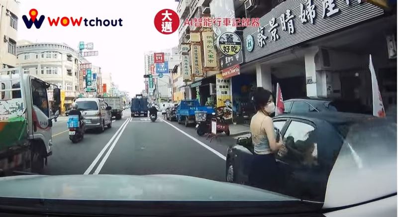 一名戴著口罩、手持飲料,穿著大露背裝露出雪白美背身材的女駕駛現身,她注意到有車輛準備經過,主動站在車門旁等待對方通過後,才上車離去。(圖/翻攝WoWtchout - 地圖型行車影像分享平台)