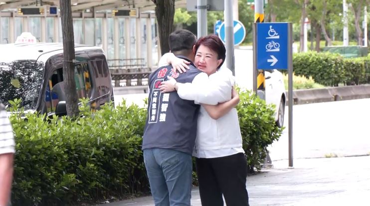 民眾路過在盧秀燕面前對著羅智強比倒讚，羅與盧見面後擁抱打氣。（圖／翻攝畫面）
