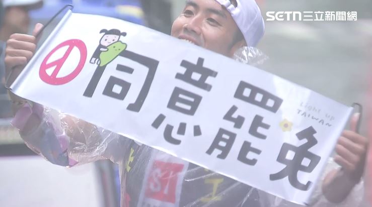 志工在雨中高舉著同意罷免布條。(圖/翻攝畫面)