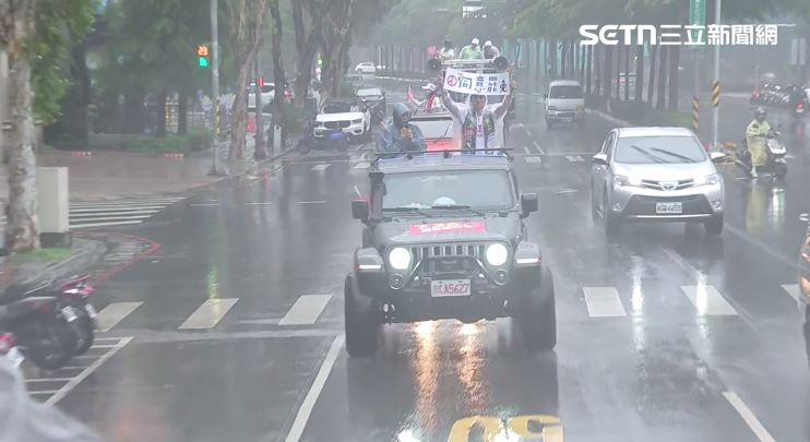志工在雨中高舉著同意罷免布條。(圖/翻攝畫面)