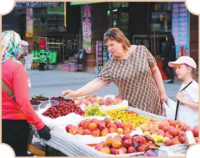 俄羅斯婦人帶著小孩在中國滿州里買水果。在滿州里,中俄兩國民眾的日常緊密交織。(圖/翻攝自中國共產黨新聞網)