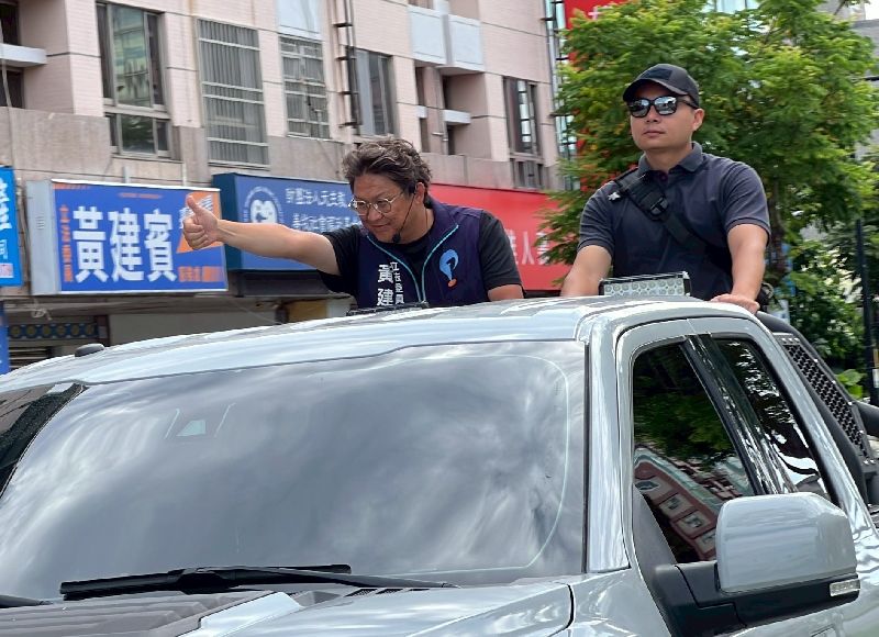國民黨立委黃建賓（左）不僅未被罷免，不同意票還比他當選立委多出9000餘張，今日一早他就展開車掃謝票行程，沿路揮手感謝支持者。（圖／中央社）