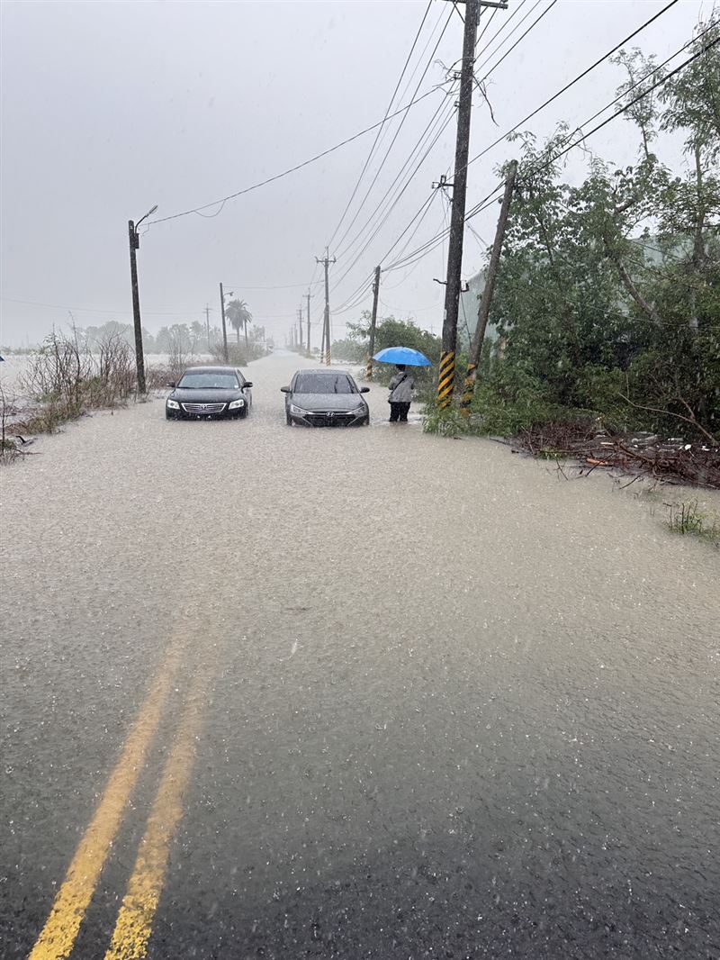 嘉義鄉道嘉22線遭豪雨灌爆,兩部車輛拋錨路中央,一名民眾撐傘苦等救援,連黨立委王育敏也陷入困境,畫面如災難電影重現。(圖/讀者提供)