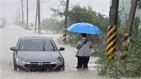 嘉義鄉道嘉22線遭豪雨灌爆，兩部車輛拋錨路中央，一名民眾撐傘苦等救援，畫面如災難電影重現。（圖／讀者提供）