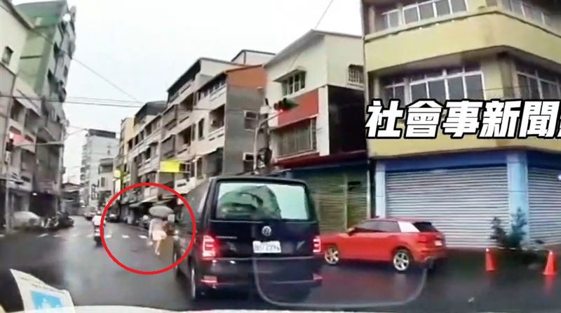 白色洋裝的女子撐傘過馬路,不過走到一半的時候突然遇到一輛黑色廂型車左轉。(圖/翻攝畫面)