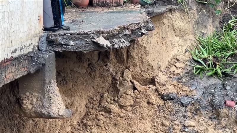 民宅下方土石不敵連日大雨崩塌，路基嚴重掏空，房子像飄浮在空中。（圖／翻攝畫面）