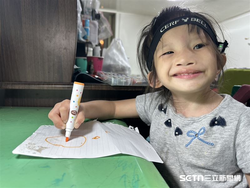 （上圖）萁萁天生失聰得配戴人工電子耳，百萬元的費用，最後也多虧是當地政府減免補助，才讓他們度過難關；（下圖）萁萁燦爛的笑容，讓人看了相當療癒。（圖／記者張雅筑攝）