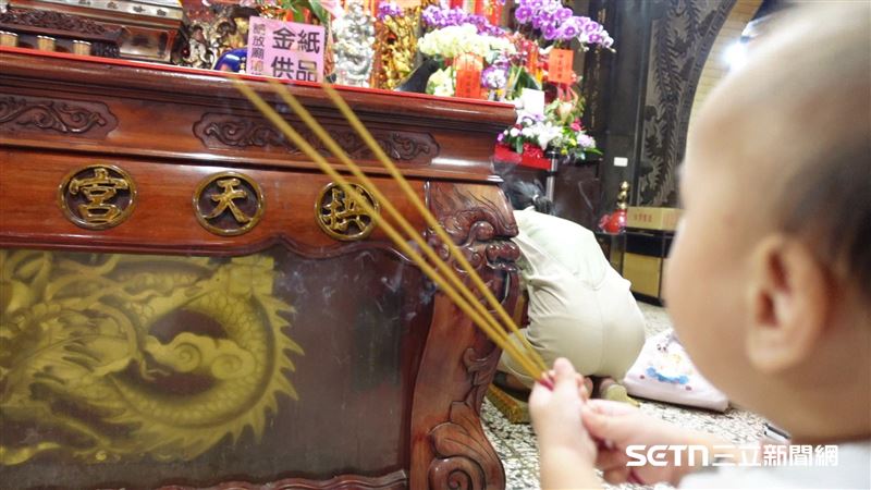 （上圖）爸爸阿蔡虔誠地跪在白沙屯媽祖前，感謝媽祖庇佑小乖乖，同時也祈求接下來的手術能順利；（下圖）小乖乖拿著香向媽祖參拜。（圖／記者張雅筑攝）