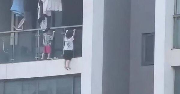 2個年幼的孩子攀爬到13樓的陽台外，用兩隻手抓著玻璃完引體向上的遊戲，看的對面鄰居嚇壞。（圖／翻攝微博）