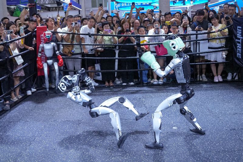 北京舉行的2025世界機器人大會現場,宇樹科技展台上演機器人格鬥賽,吸引眾多觀眾觀賽。(中新社提供)