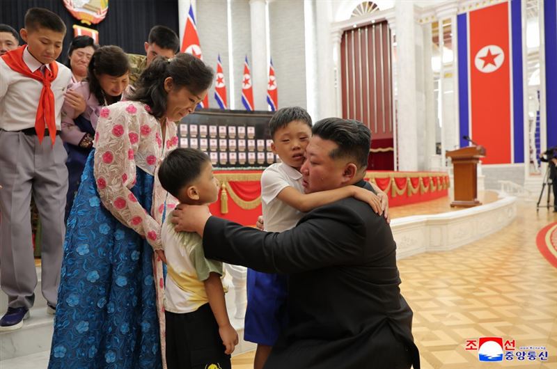 金正恩親自抱起因戰爭犧牲將士遺孀的兒女，當場落淚並致歉。（圖／翻攝自朝中社）