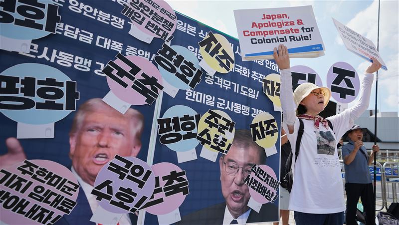 南韓總統李在明訪日、美前夕，民間團體在首爾一面手舉著有川普和石破茂照片的手牌，一面高呼主權與和平。（圖／美聯社／達志影像）