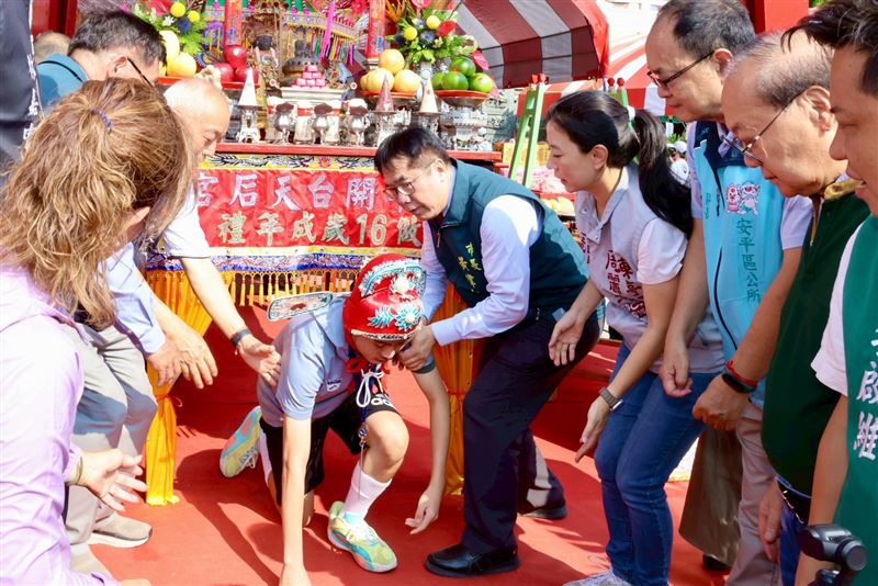 學子們戴上象徵智慧與榮耀的狀元帽，鑽出「鳥母宮」向註生娘娘、七娘媽致敬，完成「轉大人」的儀式。（圖／台南市府提供）