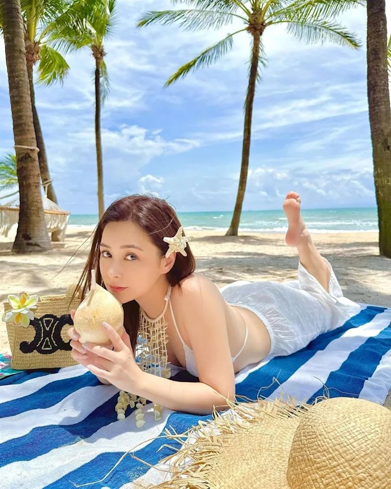 阿嬌趴在海灘墊上喝椰子水，露出事業線。（翻攝q_gill IG）
