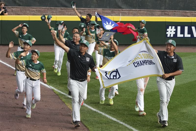 全場和全球觀眾得以看到奪冠的東園球員們拿著國旗繞場，其實是場邊的主任、校長和議員夫妻等把國旗捲成小卷後，再慢慢塞進球場的鐵絲網，才有如此歷史性的一幕。（圖／美聯社／達志影像）