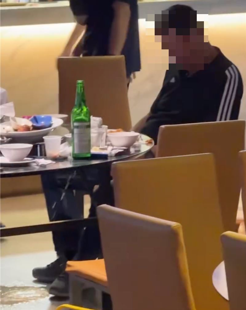 黑衣男直接在餐廳座位上小便，腳邊積了一攤尿。（圖／翻攝Threads）