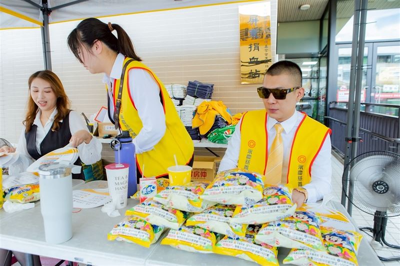 鳳梨身穿西裝搭配黃色領帶，外穿永慶房屋旗下慈善基金會的黃色背心，在捐血站前擺攤。（圖／翻攝自鳳梨Threads）