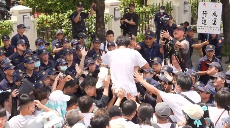 小草推倒第一層拒馬，黃國昌爬上拒馬被警方廣播。（圖／翻攝畫面）
