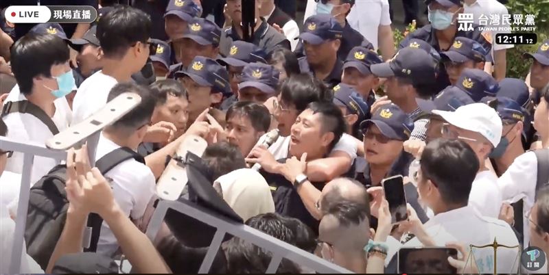 12時11分12秒，員警伸手拍打黃國昌說話並示意放手，被民眾黨指露出笑容
