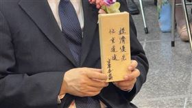 行政院長卓榮泰親手將一份牛皮紙包裝的小禮物交給新任經濟部長龔明鑫，包裝上寫著「經濟優先、任重道遠」八字箴言。龔明鑫笑稱「本來以為是糖果，結果好像是一支筆」，幽默化解媒體追問，也展現輕鬆一面，緊張莊重的典禮現場因此添上幾分趣味。（圖／記者師瑞德攝影）