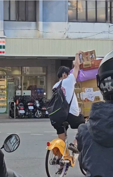 一名男子單手騎單車，另一手扶著疊到比人高的包裹，在台中市健行路上逆向又闖紅燈。（圖／翻攝自Thread @hln.lin）)